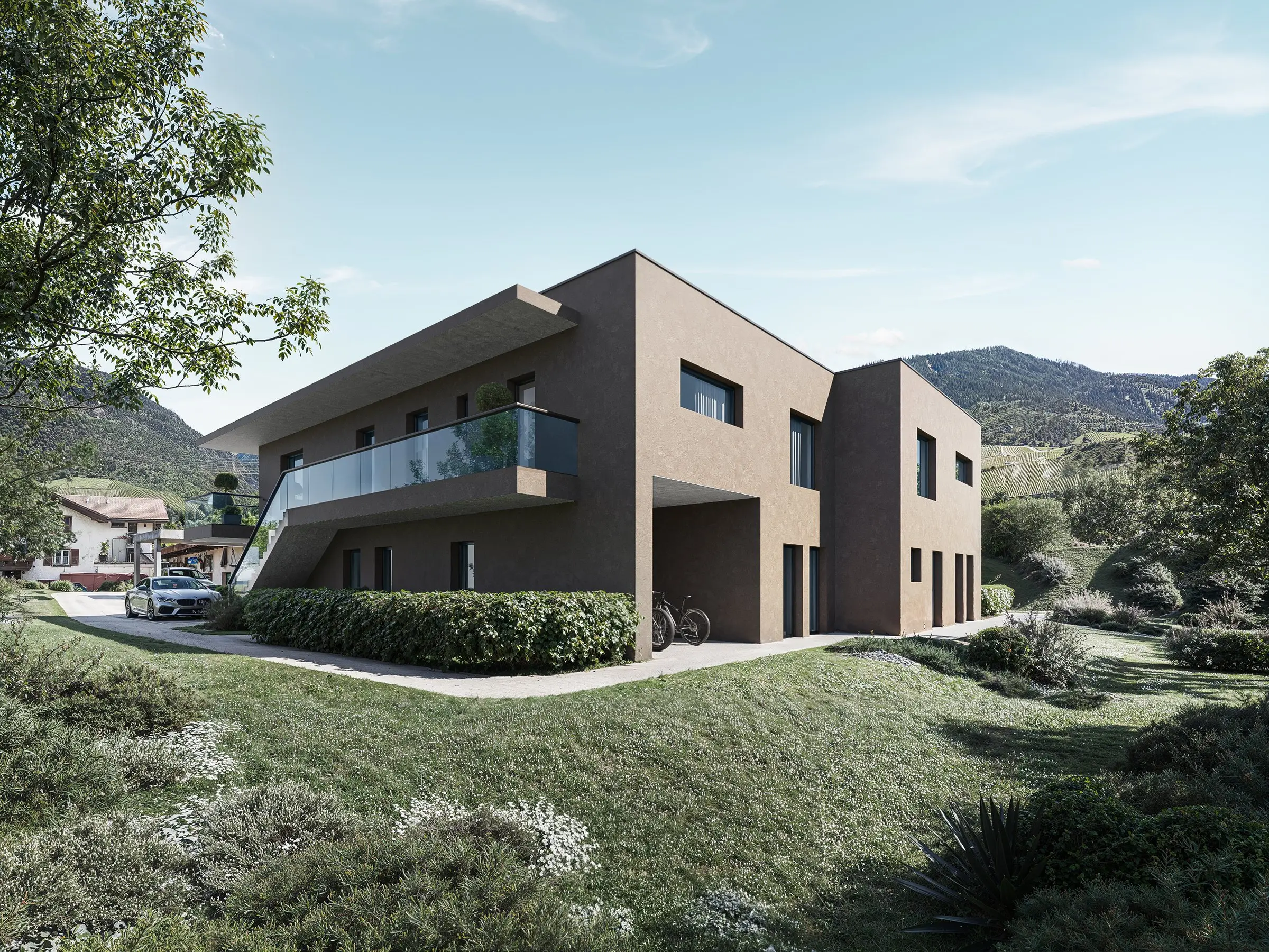 Les deux maisons contiguës de Réchy, façades brun foncé, balcons à l'étage et jardins au rez, coteau en arrière-plan